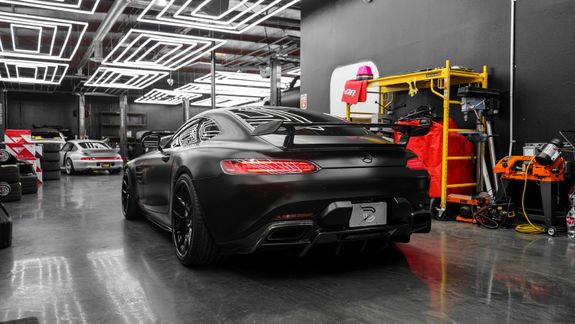 Sleek black luxury car parked in a modern, well-lit garage with a polished floor.