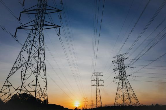 Scenery of contemporary electric power transmission lines located against picturesque sunset sky in evening countryside