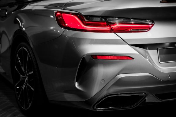 Detailed view of a sleek grey car's rear featuring illuminated red brake light and exhaust.