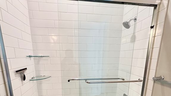 Anonymous person wearing yellow latex gloves washing golden faucet with sponge in modern bathroom while cleaning house