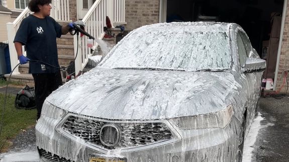 Detailed view of a sleek black car's taillight with red illumination, reflecting dusk light.