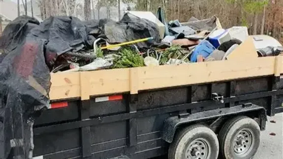 White Mack truck loaded with cargo travels on a scenic road by a lake under a blue sky.