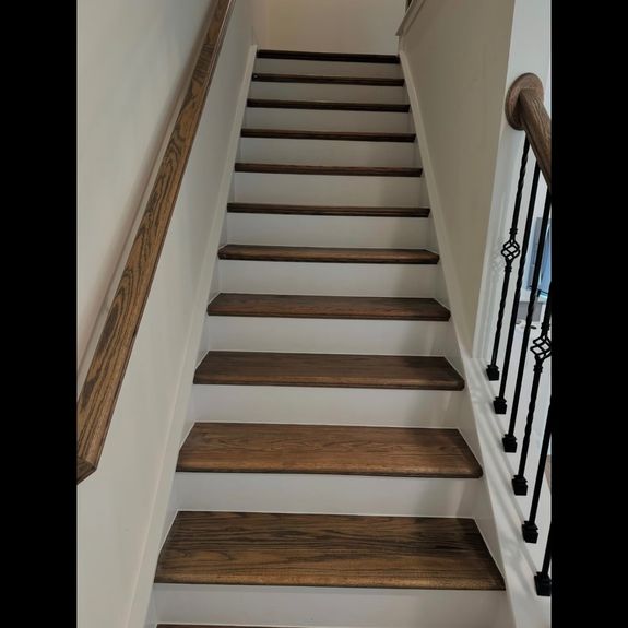 A long white kitchen with wooden floors and a window