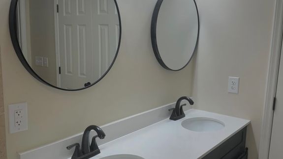 Anonymous person in yellow rubber gloves using simple sponge for cleaning mirror in bathroom