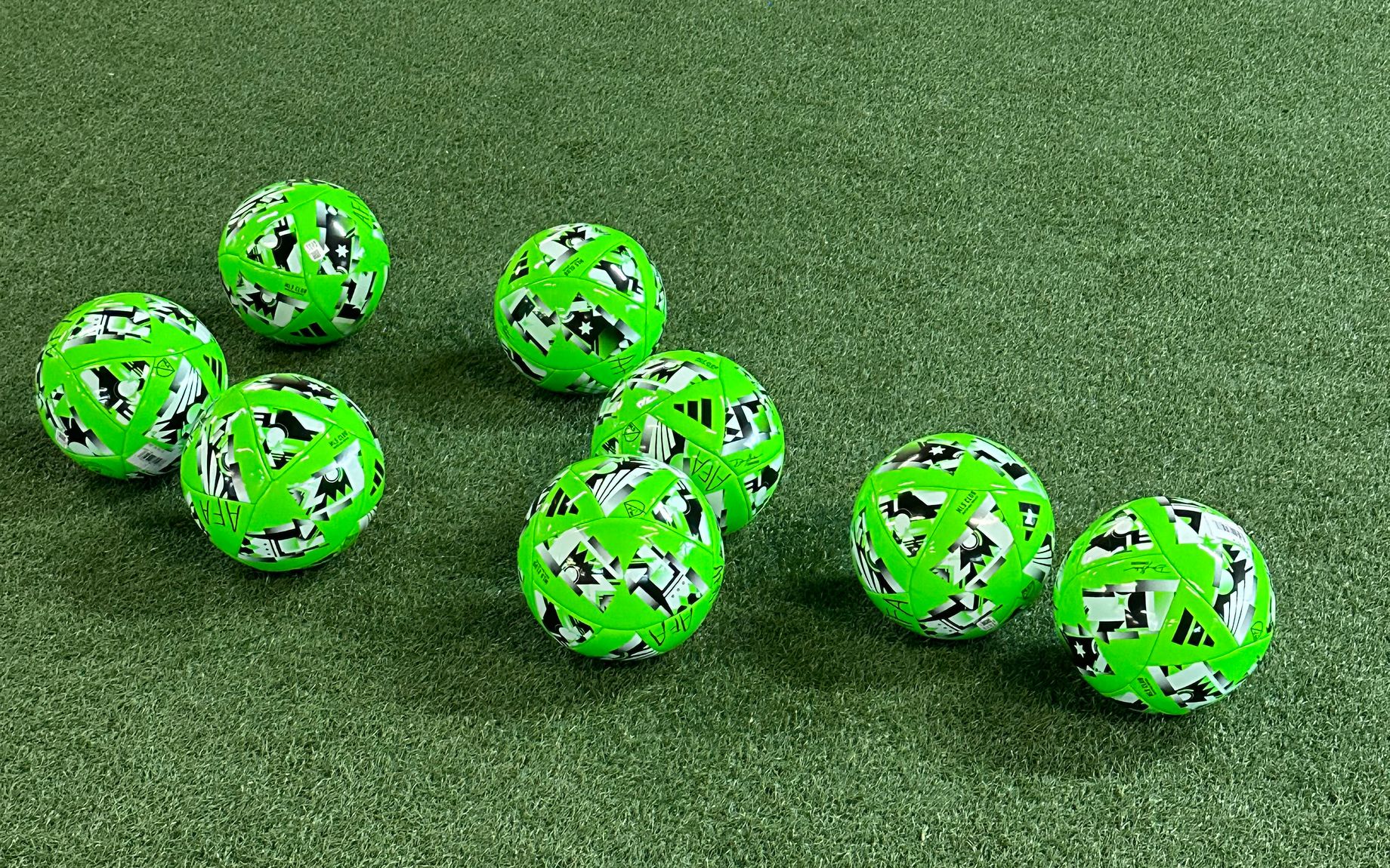 Green soccer balls on indoor soccer field turf
