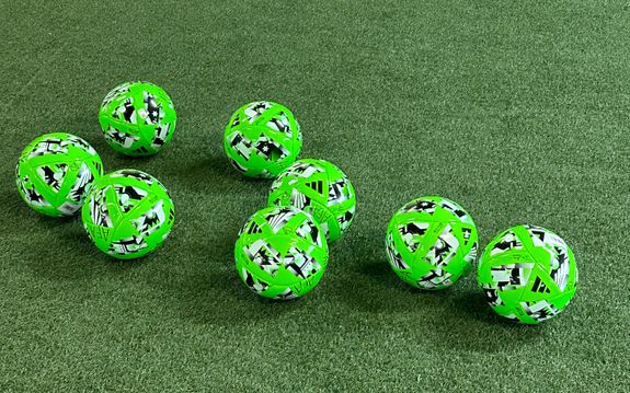 Green soccer balls on indoor soccer field turf