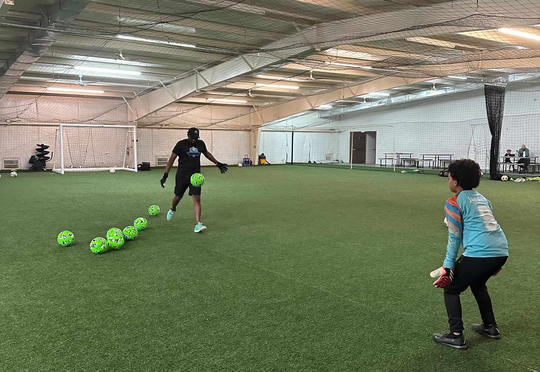Coach and player practicing soccer drills on an indoor soccer field