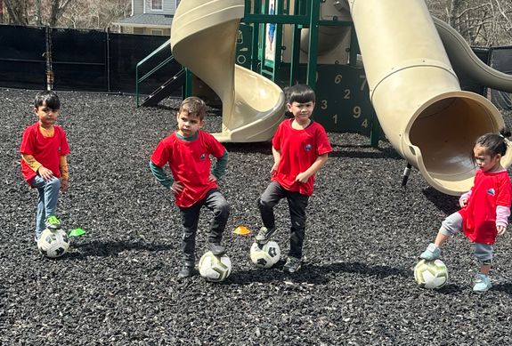 A group of children with soccer balls at a soccer camp