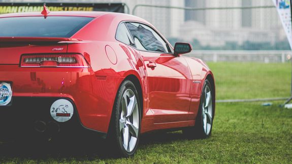 Detailed view of a shiny red car's tail light with bokeh reflections.