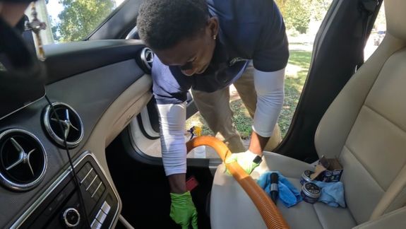 Sleek black luxury car parked in a modern, well-lit garage with a polished floor.