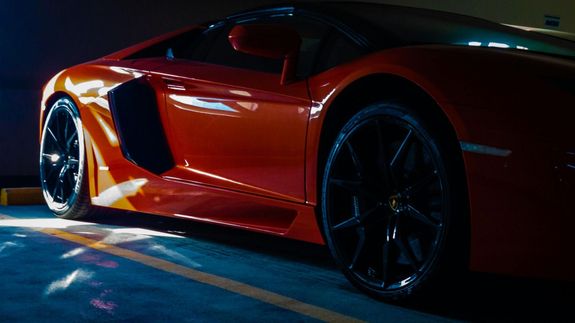 Detailed view of a shiny red car's tail light with bokeh reflections.