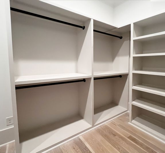 Custom-built closet with open shelves and black hanging rods