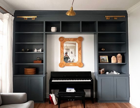 Custom-made charcoal blue built in shelves and cabinets with brass hardware