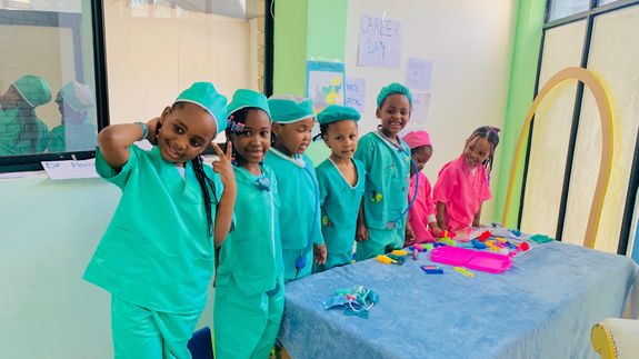 Girl In White Long Sleeve Dress Sitting On Brown Wooden Chair Cutting Paper